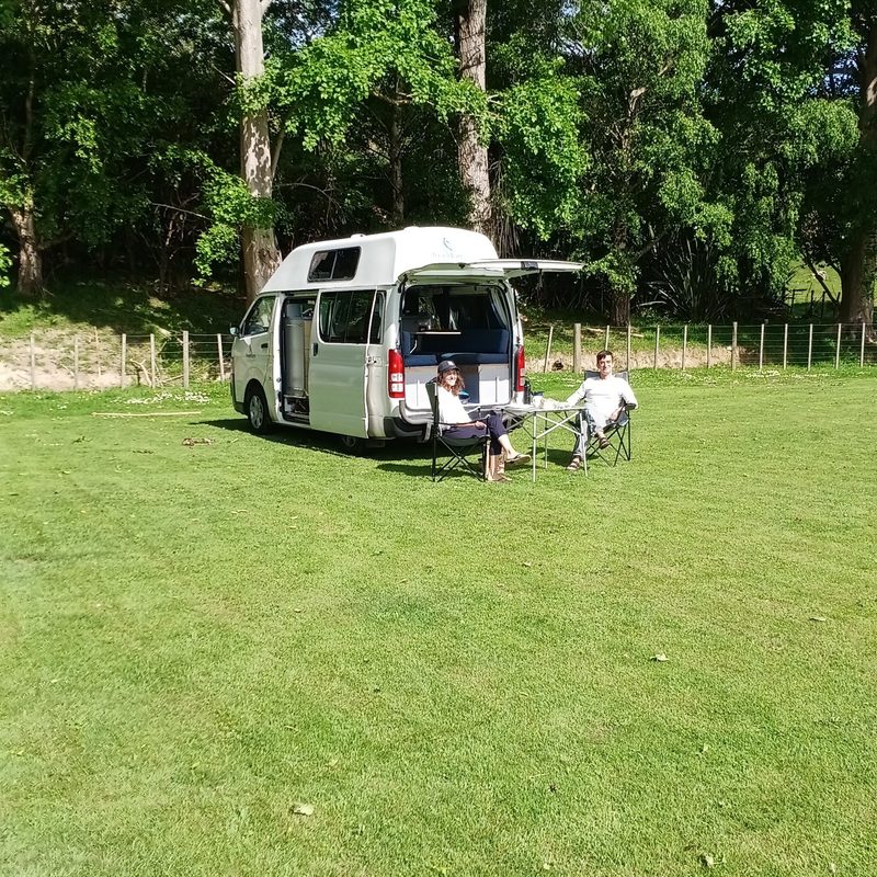 Couple relaxing beside their campervan on the rugby field