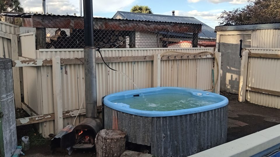 Wood-fired hot tub with fire stoked beside it